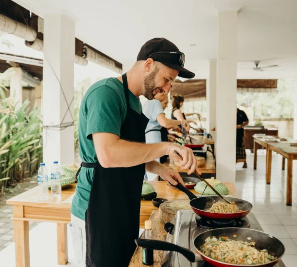 Students enthusiastically learn to cook local dishes from an expert chef in Bali.